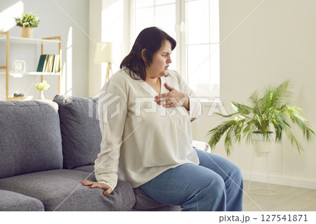 Overweight young woman clutching her chest suffering from pain Overweight young woman clutching her chest suffering from pain 127541871