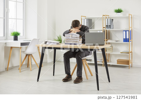 Exhausted worker tired of overworking sleeping on stacks of folders with documents in office. 127541981