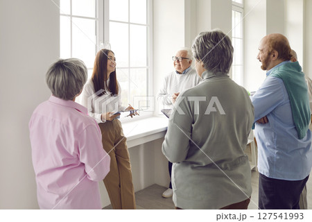 Group of seniors listening psychologist woman speaking on a meeting in nursing home. 127541993