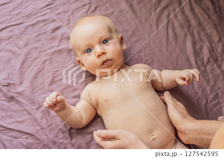 Newborn baby lying on a soft blanket while mother gently exercises the babys tiny limbs. Early development, bonding, and baby care concept 127542595