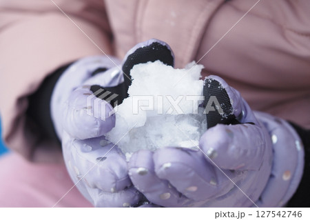 Child plays with snow in warm gloves on a winter day 127542746