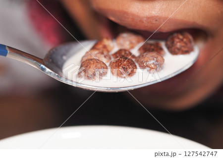 Spoonful of chocolate cereal with milk at breakfast 127542747