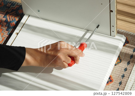 Assembling furniture with a screwdriver in a bright room Assembling furniture with a screwdriver in a bright room 127542809