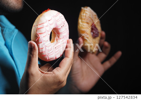 Colorful donuts held by a person in dark background Colorful donuts held by a person in dark background 127542834