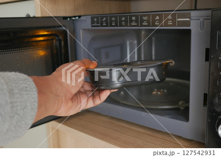 Heating food in the microwave at home kitchen 127542931
