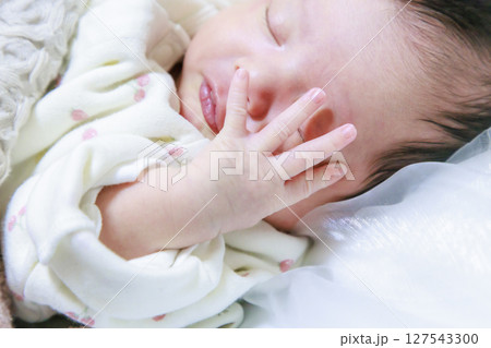顔に手を当てて眠る赤ちゃん　新生児 127543300