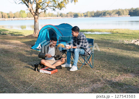 couple gay lgbt sitting in camp cooking and near river in mountains. Camping couple lgbt concept couple gay lgbt sitting in camp cooking and near river in mountains. Camping couple lgbt concept 127543503