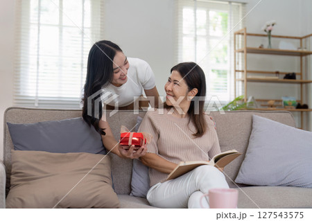 Congratulations. Loving asian mature daughter surprised mother with present in Mother's Day, giving her handmade card and gift box Congratulations. Loving asian mature daughter surprised mother with present in Mother's Day, giving her handmade card and gift box 127543575