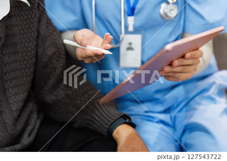 Doctor or nurse caregiver showing prescription or document and holding drug bottle to senior man at home or nursing home Doctor or nurse caregiver showing prescription or document and holding drug bottle to senior man at home or nursing home 127543722