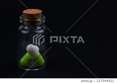 glass jar with green and white pills glass jar with green and white pills 127544422