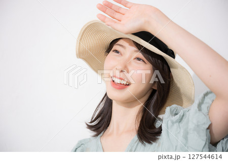 麦わら帽子を被って眩しい日焼けを気にする夏服の女性　お出かけや夏休み、旅行レジャーなどのイメージ 127544614