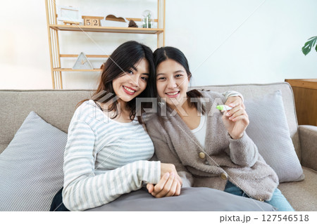 Two happy gay lesbian lgbt women couple sitting on sofa celebrating positive pregnancy test. lgbtq concept Two happy gay lesbian lgbt women couple sitting on sofa celebrating positive pregnancy test. lgbtq concept 127546518