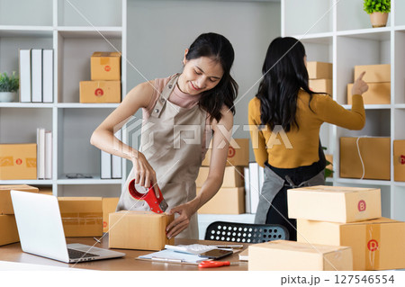 Young business entrepreneur sealing a box with tape. Preparing for shipping, Packing, online selling, e-commerce concept Young business entrepreneur sealing a box with tape. Preparing for shipping, Packing, online selling, e-commerce concept 127546554