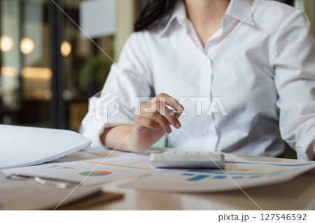 Business accountant engaged in financial analysis, using a calculator and discussing data Business accountant engaged in financial analysis, using a calculator and discussing data 127546592