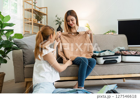 Two women friends packing suitcases for holiday. happily choose clothes together for the holiday Two women friends packing suitcases for holiday. happily choose clothes together for the holiday 127546618