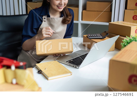Young business entrepreneur using laptop. Preparing for shipping, online selling, e-commerce concept Young business entrepreneur using laptop. Preparing for shipping, online selling, e-commerce concept 127546691