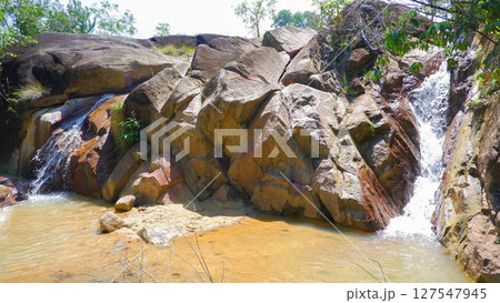 Small Rocky Waterfall Flowing into Shallow Pond in Tropical Forest 127547945