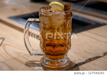 A glass of whiskey with lemon and cinnamon, on the table 127548263