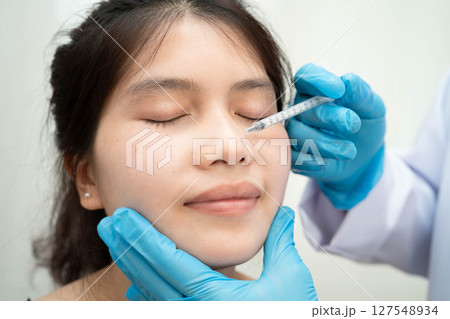 Asian woman receiving filler face beauty injection. 127548934