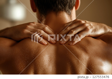 Man Seeking Relief as He Rubs His Painful Back Under Warm Lighting in a Serene Indoor Space 127553476