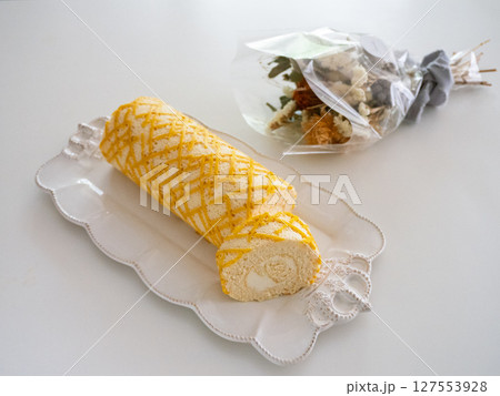 チーズロールケーキ、白い皿、造花 チーズロールケーキ、白い皿、造花 127553928