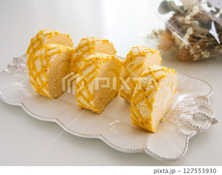 チーズロールケーキ、白い皿、造花 チーズロールケーキ、白い皿、造花 127553930