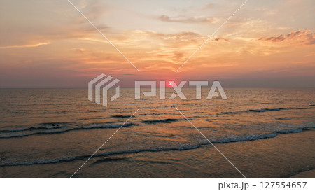 Stunning sunset illuminating calm ocean waves at dusk Stunning sunset illuminating calm ocean waves at dusk 127554657