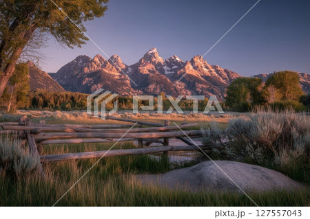 The scene of a colorful spring sunset at the Teton Range, as viewed from an abandoned old ranch in the Mormon Row historic district, is referred to as the Golden Fiery Sunset at Grand Teton, located 127557043