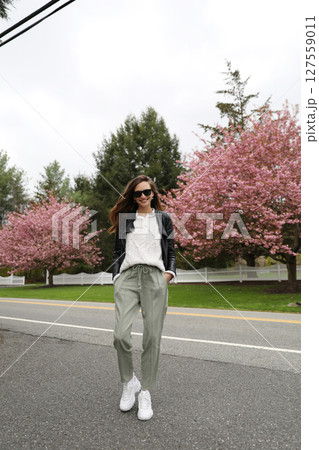 Young smiling brunette woman against a background of blooming trees 127559011