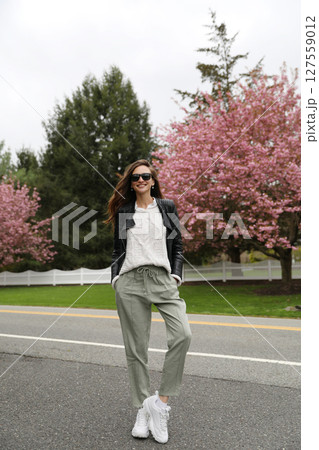 Young smiling brunette woman against a background of blooming trees Young smiling brunette woman against a background of blooming trees 127559012