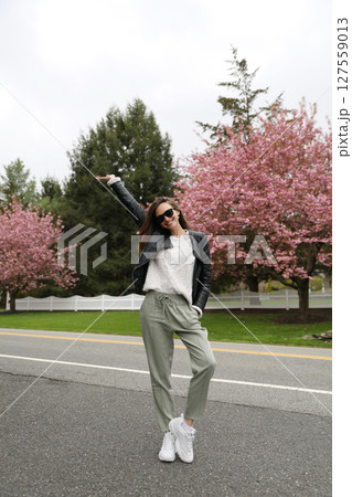 Young smiling brunette woman against a background of blooming trees 127559013