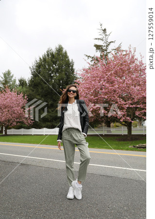 Young smiling brunette woman against a background of blooming trees Young smiling brunette woman against a background of blooming trees 127559014