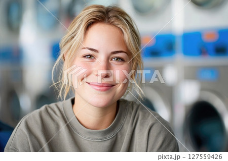 Young Blonde Woman Smiling at Laundromat Young Blonde Woman Smiling at Laundromat 127559426