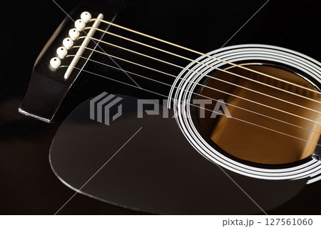 Guitar black stringed plucked musical instrument, lower threshold, close-up selective focus Guitar black stringed plucked musical instrument, lower threshold, close-up selective focus 127561060