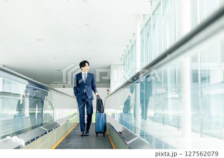 キャリーバッグを持って歩く若い男性 キャリーバッグを持って歩く若い男性 127562079
