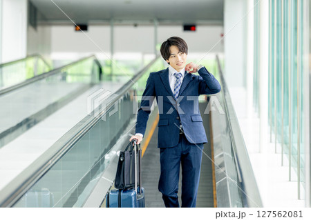 キャリーバッグを持って歩く若い男性 キャリーバッグを持って歩く若い男性 127562081