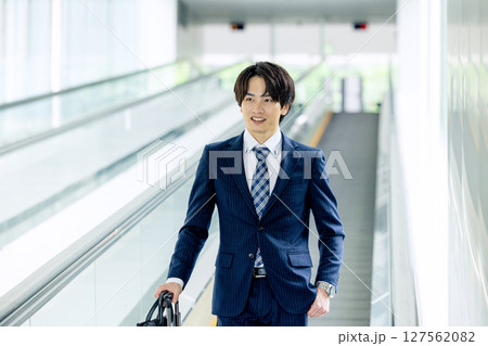 キャリーバッグを持って歩く若い男性 127562082