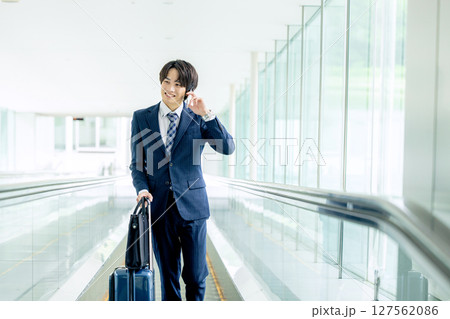 キャリーバッグを持って歩く若い男性 127562086