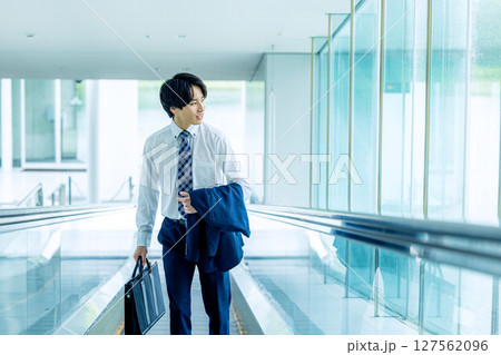 キャリーバッグを持って歩く若い男性 127562096