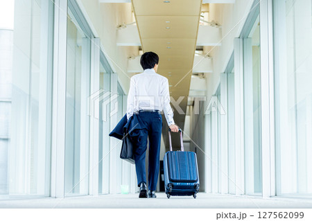 キャリーバッグを持って歩く若い男性 127562099