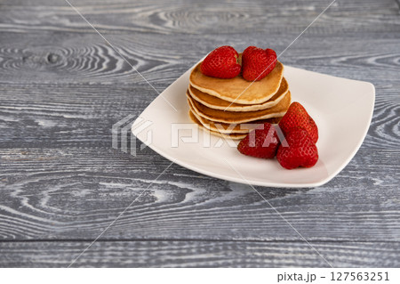 Pancakes with berries on a white plate on the table Pancakes with berries on a white plate on the table 127563251