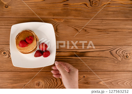 Pancakes with berries on a white plate on the table 127563252