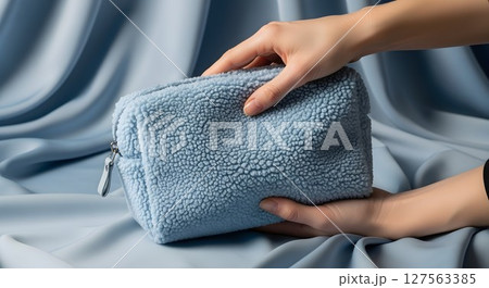 Woman showing blue cosmetic bag. Beauty care product for makeup and travel. Soft textile accessory for everyday use. 127563385