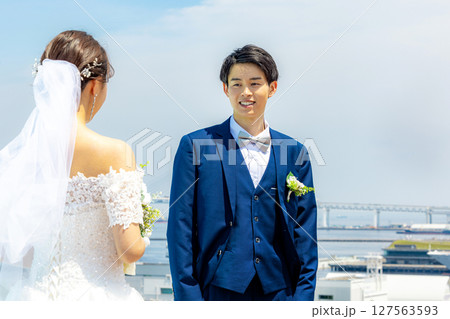 青空の下で笑顔で立つ新郎新婦 127563593