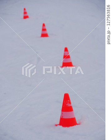 A row of orange cones are in the snow A row of orange cones are in the snow 127563816