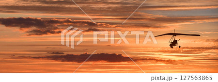 Hang glider on a motor on a summer evening against the backdrop of a sunset sky. Extreme sport. Banner, blank for an advertising layout with a place for writing Hang glider on a motor on a summer evening against the backdrop of a sunset sky. Extreme sport. Banner, blank for an advertising layout with a place for writing 127563865