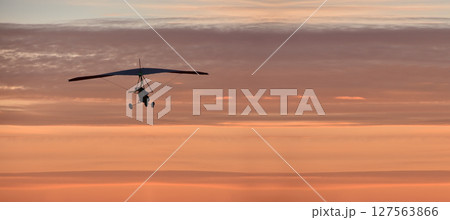 Hang glider on a motor on a summer evening against the backdrop of a sunset sky. Extreme sport. Banner, blank for an advertising layout with a place for writing Hang glider on a motor on a summer evening against the backdrop of a sunset sky. Extreme sport. Banner, blank for an advertising layout with a place for writing 127563866
