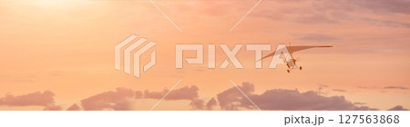 Hang glider on a motor on a summer evening against the backdrop of a sunset sky. Extreme sport. Banner, blank for an advertising layout with a place for writing 127563868