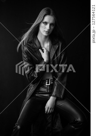 Timeless intensity - black and white portrait of a woman in leather, seated with a strong pose, her intense gaze radiating power and confidence, contrasted against a dark backdrop for a cinematic edge Timeless intensity - black and white portrait of a woman in leather, seated with a strong pose, her intense gaze radiating power and confidence, contrasted against a dark backdrop for a cinematic edge 127564121