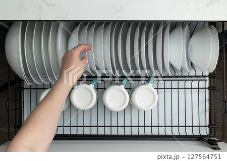 Organizing Clean Dishes and Cups in a Modern Kitchen Cabinet After Washing Organizing Clean Dishes and Cups in a Modern Kitchen Cabinet After Washing 127564751
